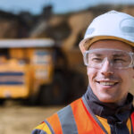 Mine worker with huge truck on the background in open pit
